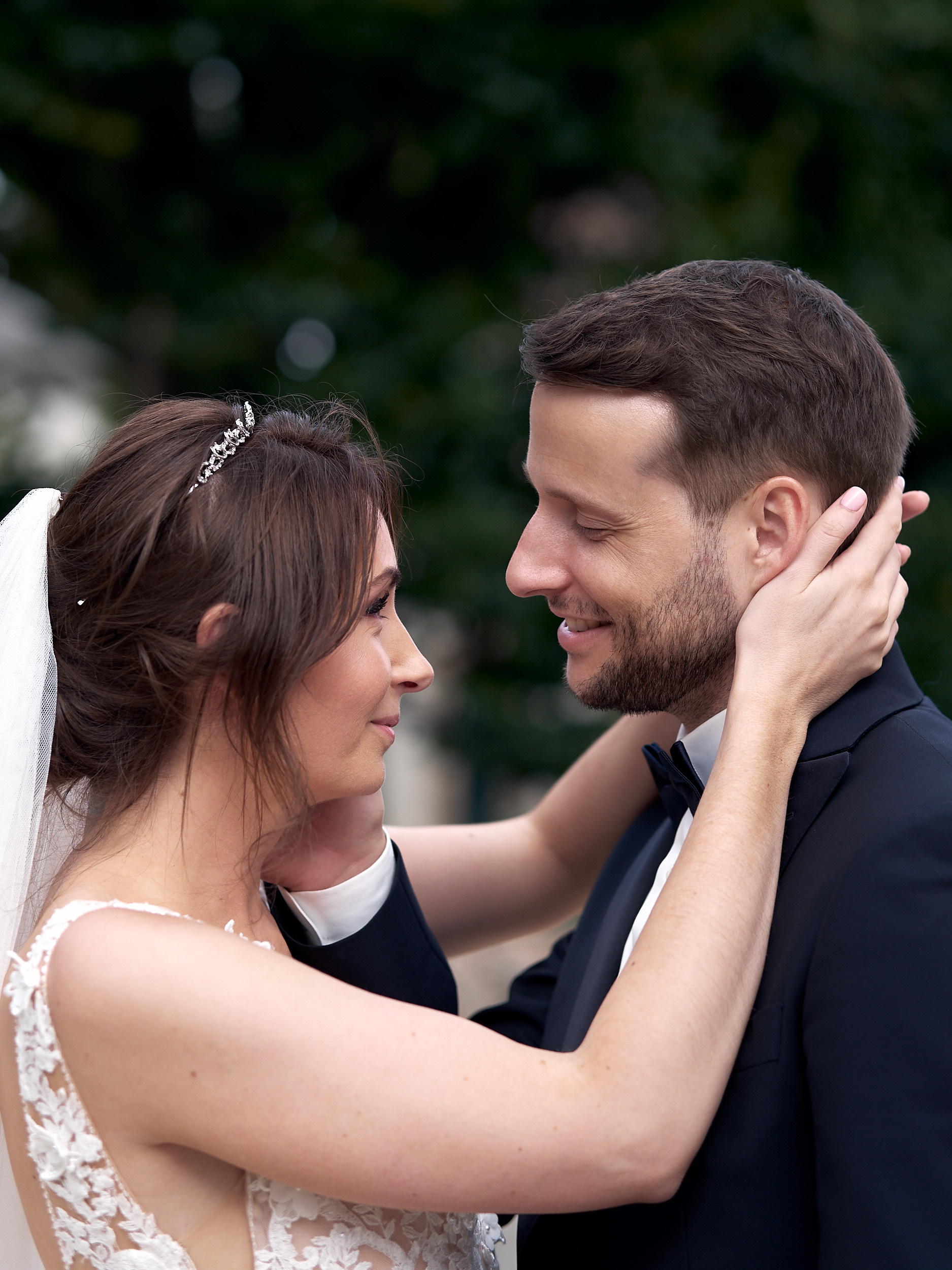 Mariée passant les bras autour du cou du marié, leurs visages rapprochés.