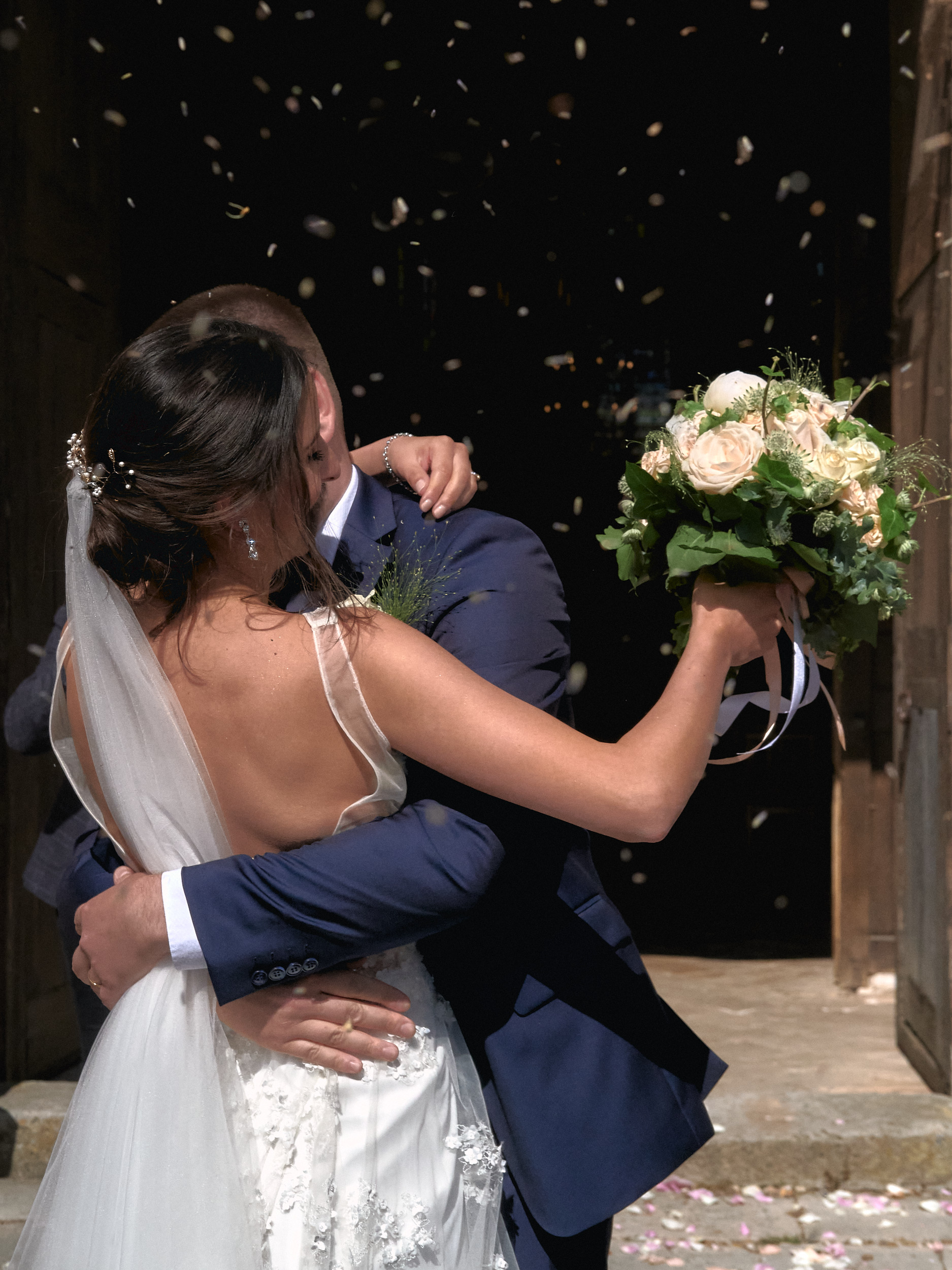 Mariés s’embrassant à la sortie d’une église sous une pluie de confettis.